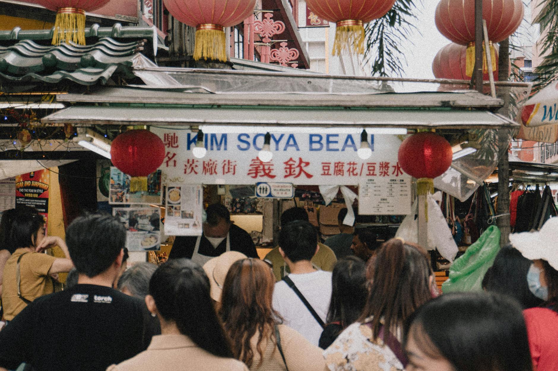 a crowd of people standing in front of a food stand